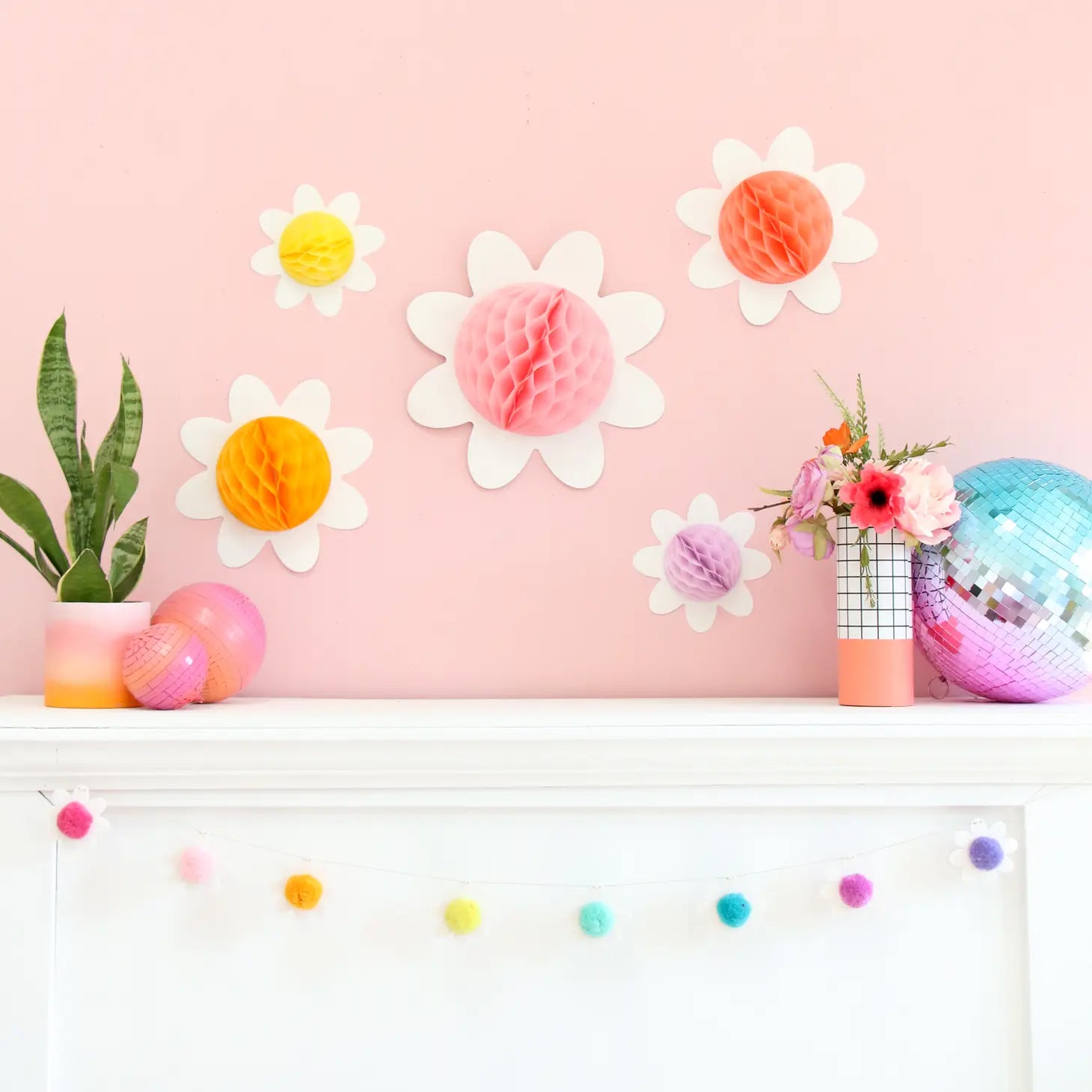 Pastel Daisy Flower Honeycomb decorations on a pink wall above mantel piece